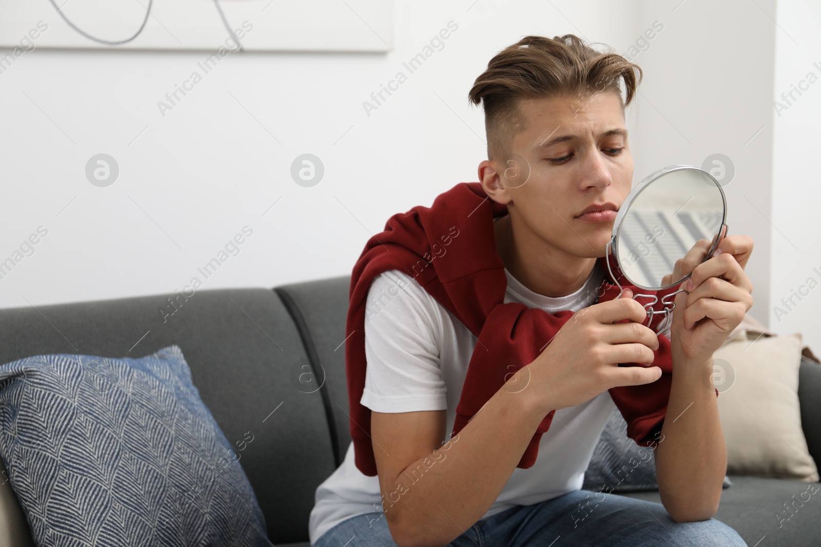 Photo of Handsome man looking at mirror on sofa at home