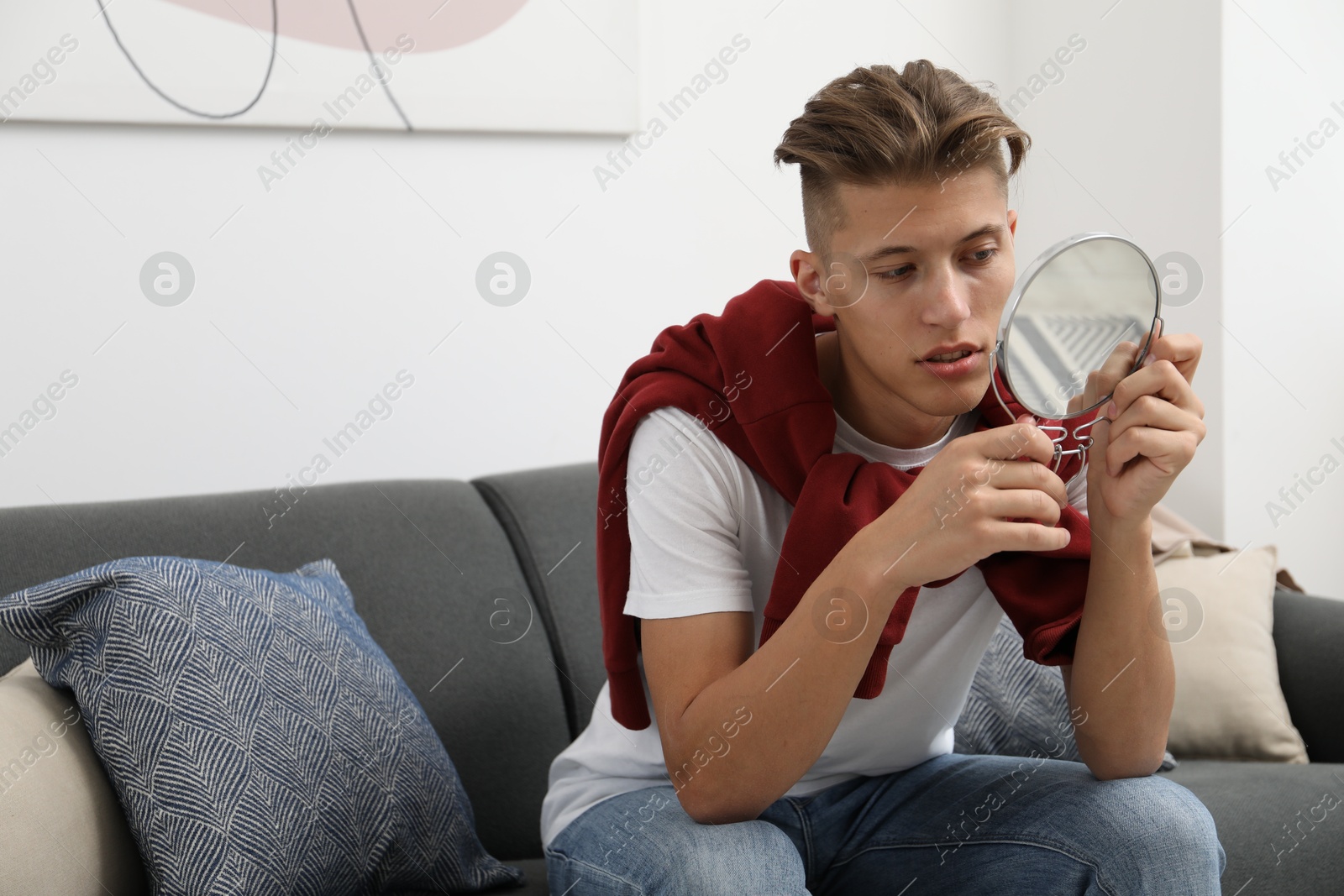 Photo of Handsome man looking at mirror on sofa at home