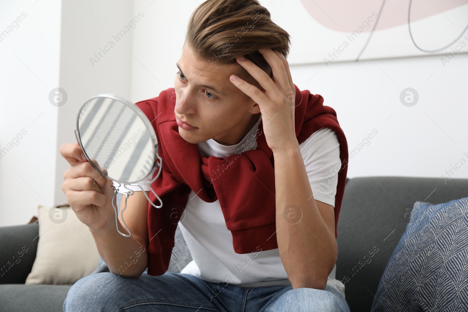 Photo of Handsome man looking at mirror on sofa at home