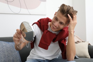 Photo of Handsome man looking at mirror on sofa at home