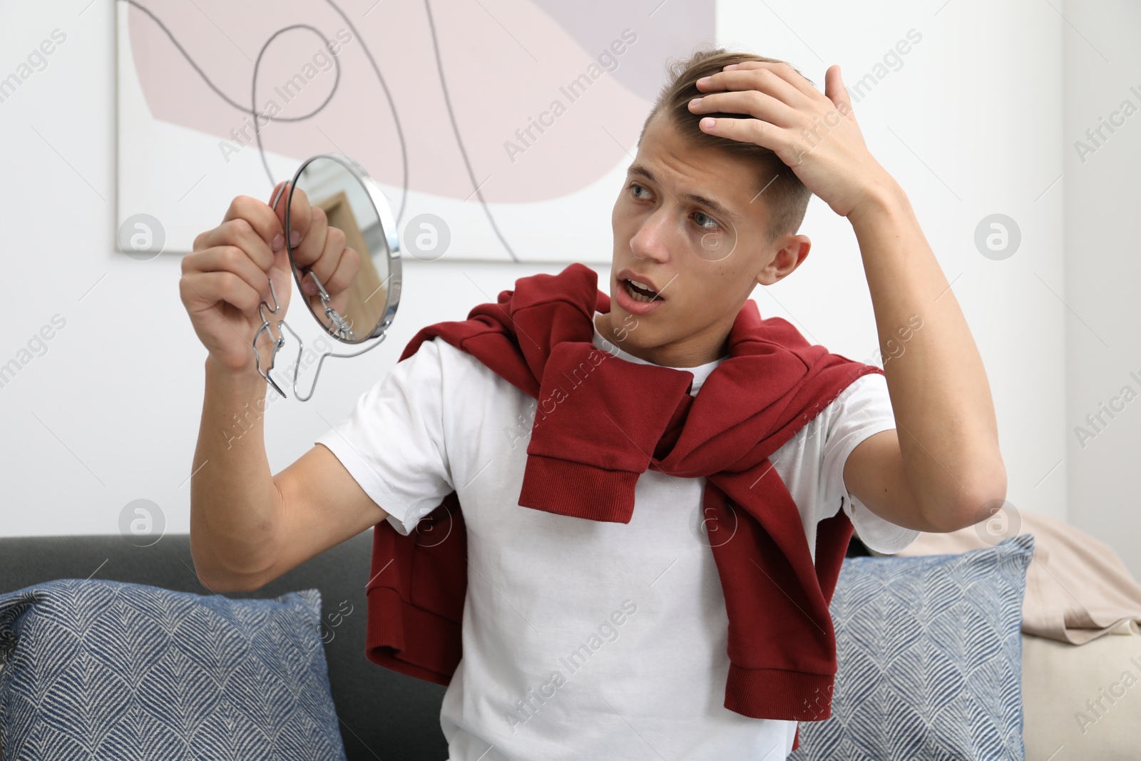 Photo of Man with mirror examining his head indoors