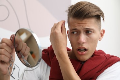 Man with mirror examining his hair indoors