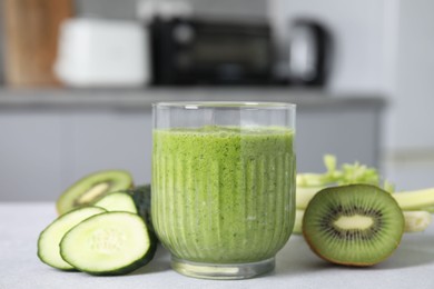 Photo of Delicious green smoothie and ingredients on light table, closeup