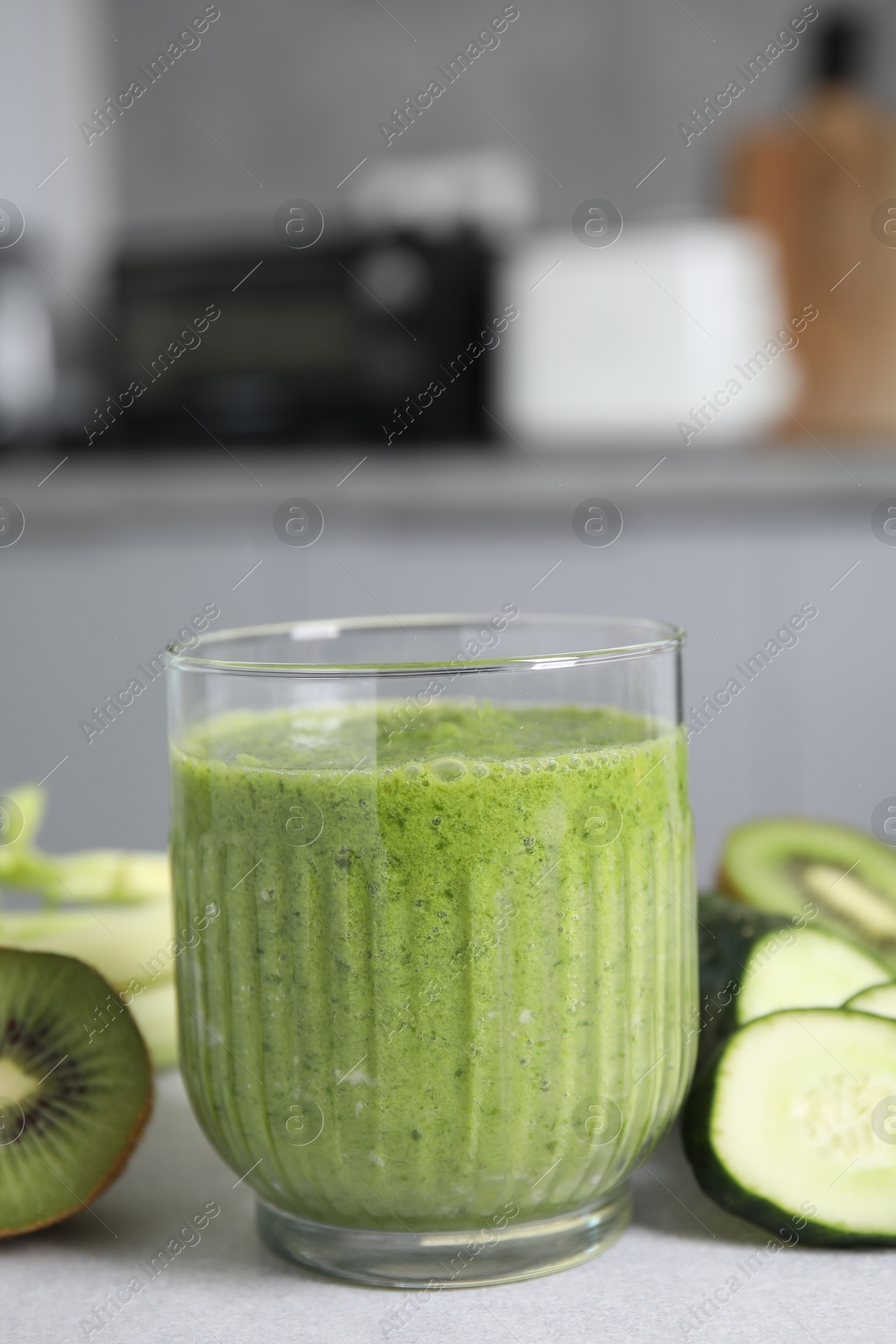 Photo of Delicious green smoothie and ingredients on light table