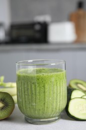 Photo of Delicious green smoothie and ingredients on light table