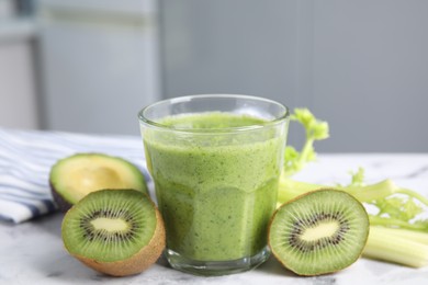 Photo of Delicious green smoothie and ingredients on white table, closeup