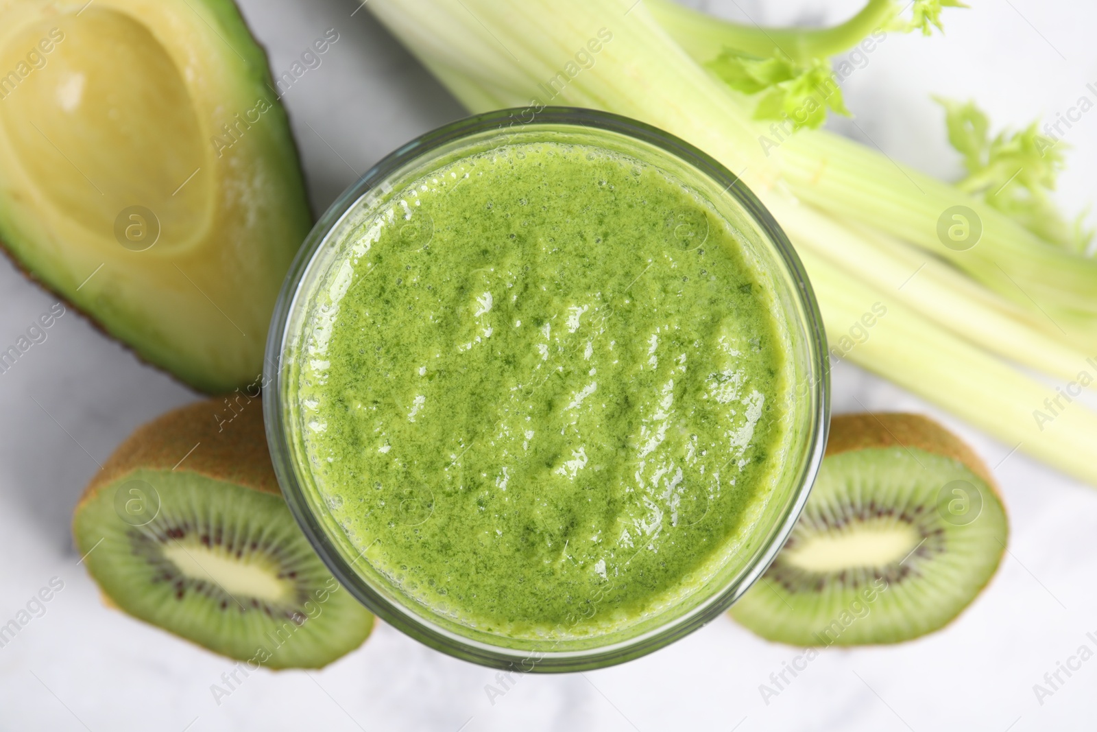 Photo of Delicious green smoothie and ingredients on white table, top view