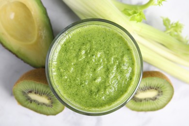 Photo of Delicious green smoothie and ingredients on white table, top view