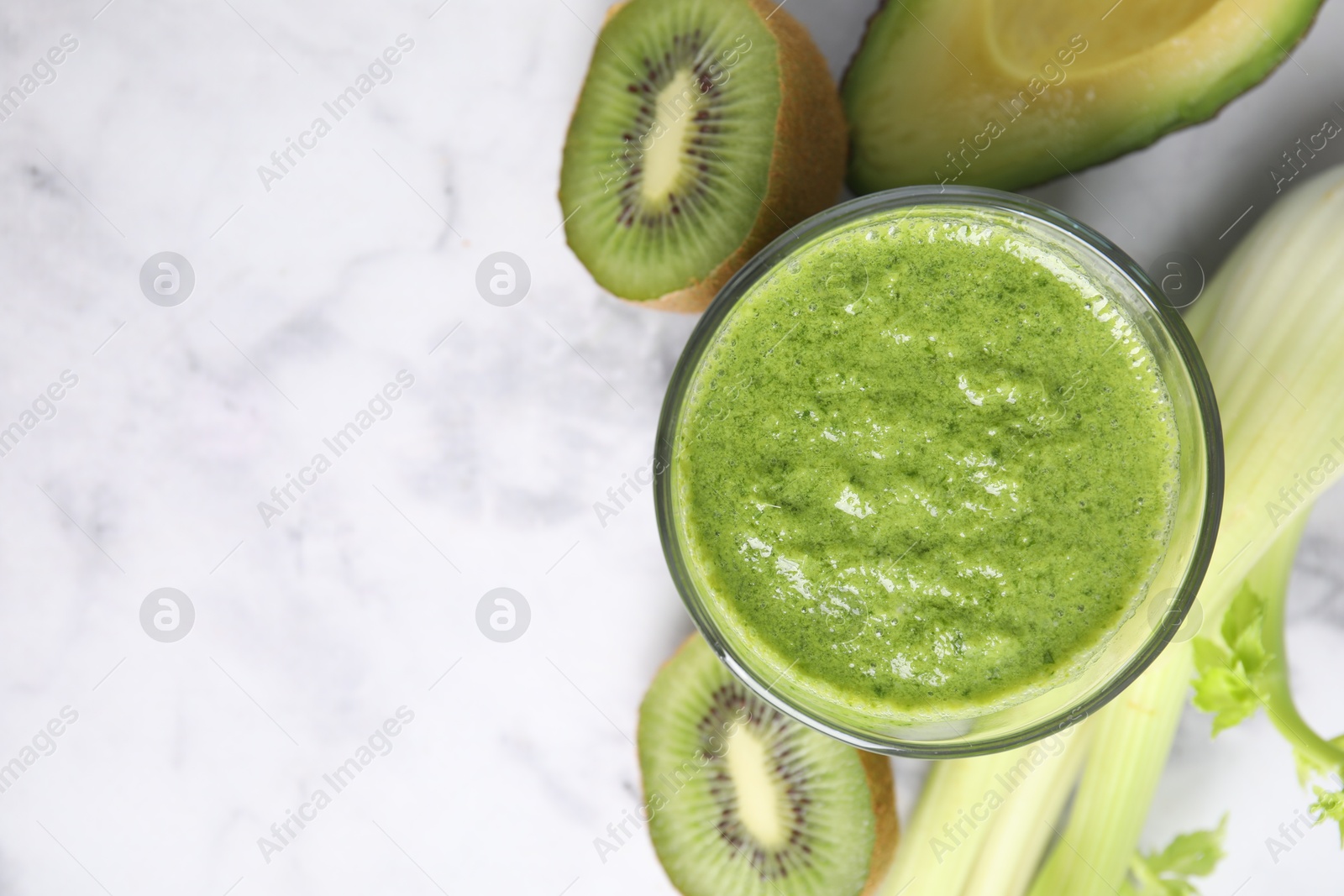 Photo of Delicious green smoothie and ingredients on white marble table, top view. Space for text