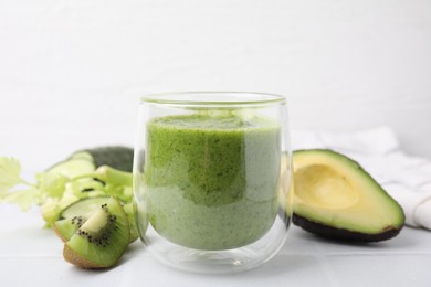 Delicious green smoothie and ingredients on white table