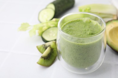 Photo of Delicious green smoothie and ingredients on white table, closeup. Space for text