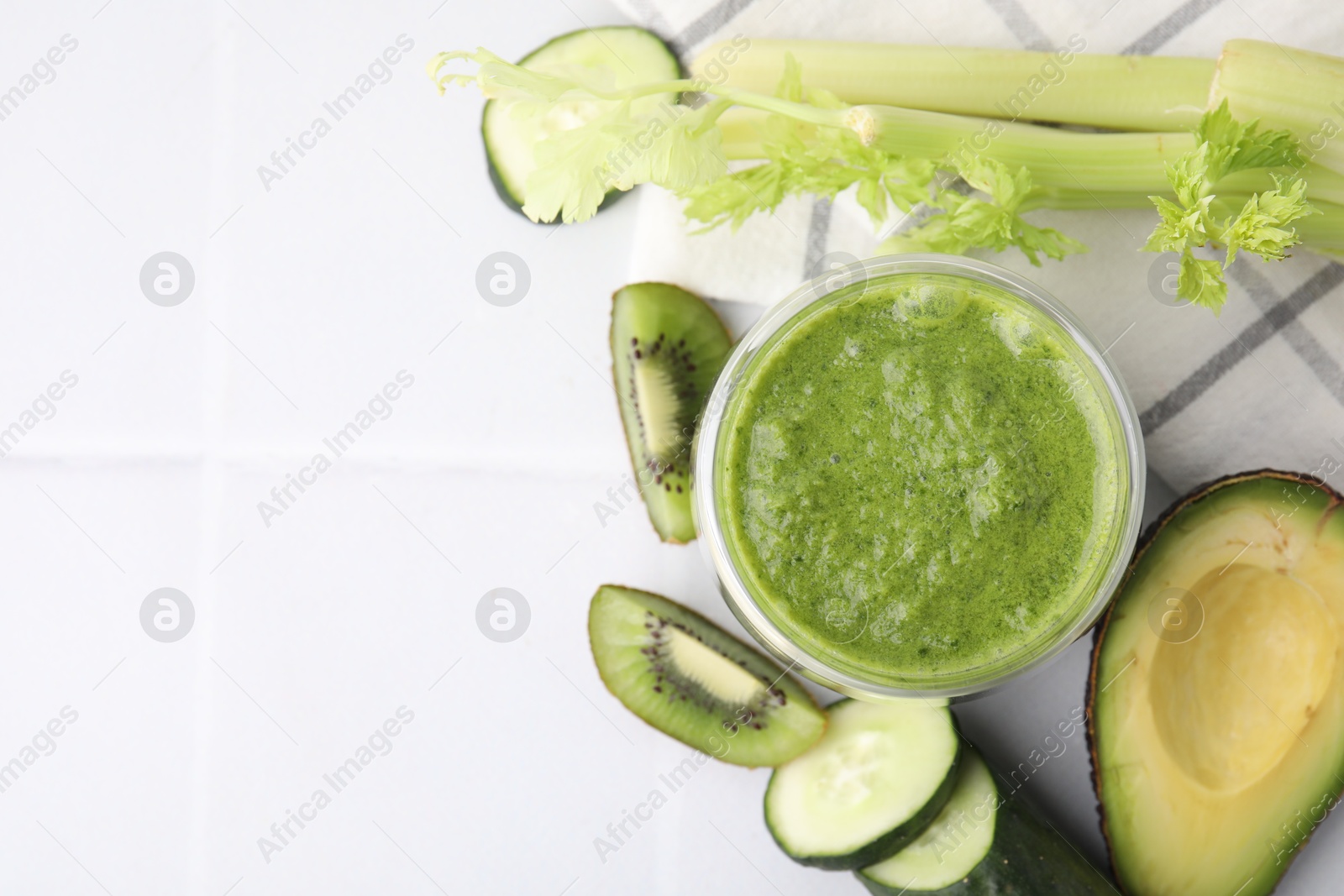 Photo of Delicious green smoothie and ingredients on white table, top view. Space for text