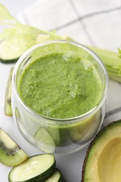 Photo of Delicious green smoothie and ingredients on white table