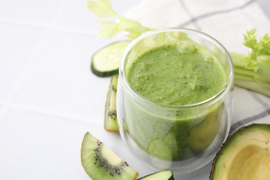 Photo of Delicious green smoothie and ingredients on white table, closeup. Space for text