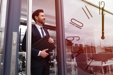 Businessman walking out of office building, clock, double exposure. Time management