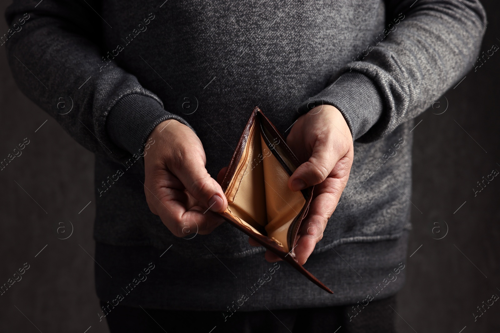 Photo of Man with empty wallet on dark background, closeup