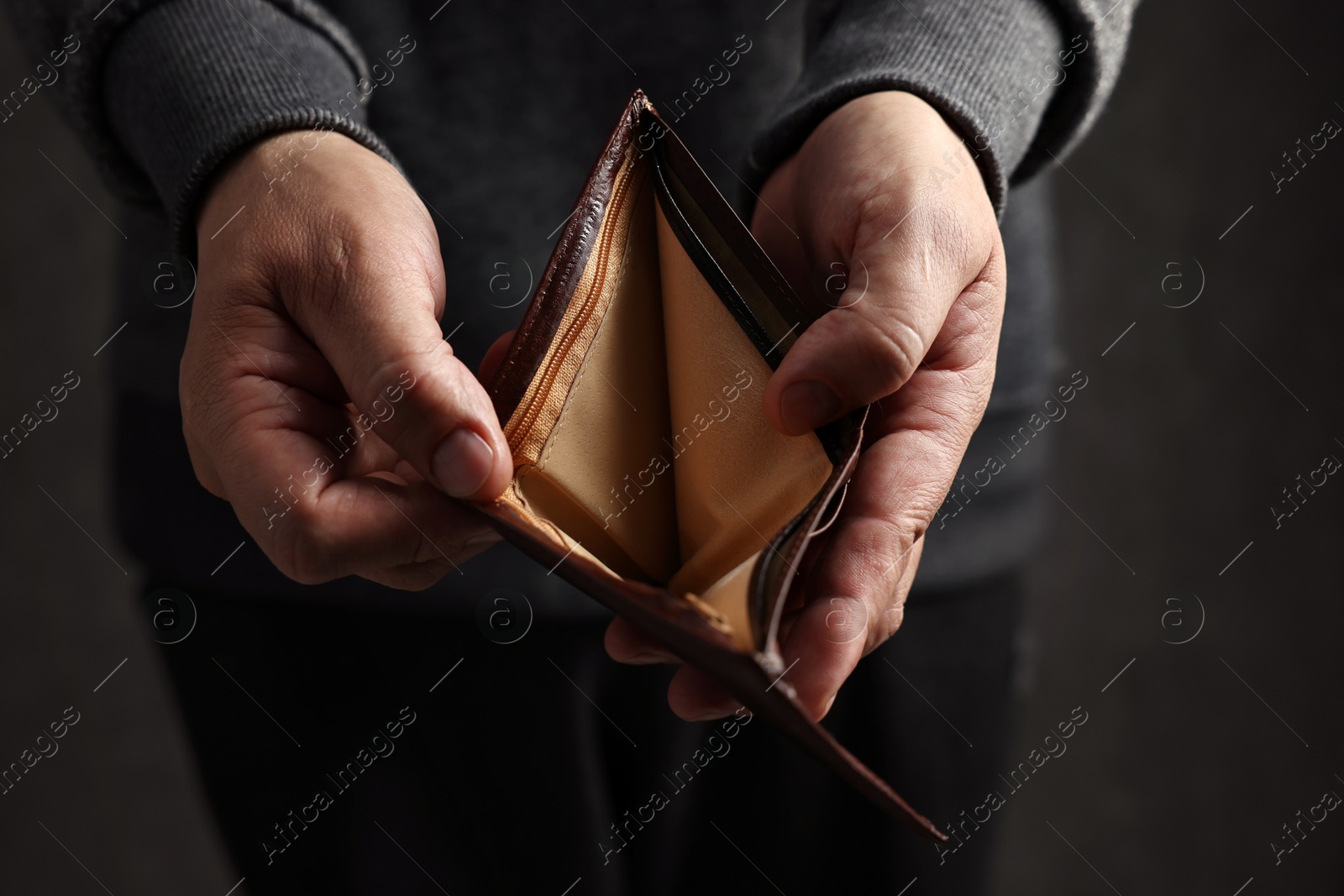 Photo of Man with empty wallet on dark background, closeup