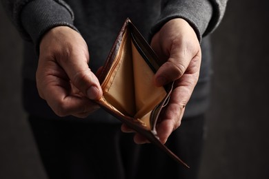 Photo of Man with empty wallet on dark background, closeup