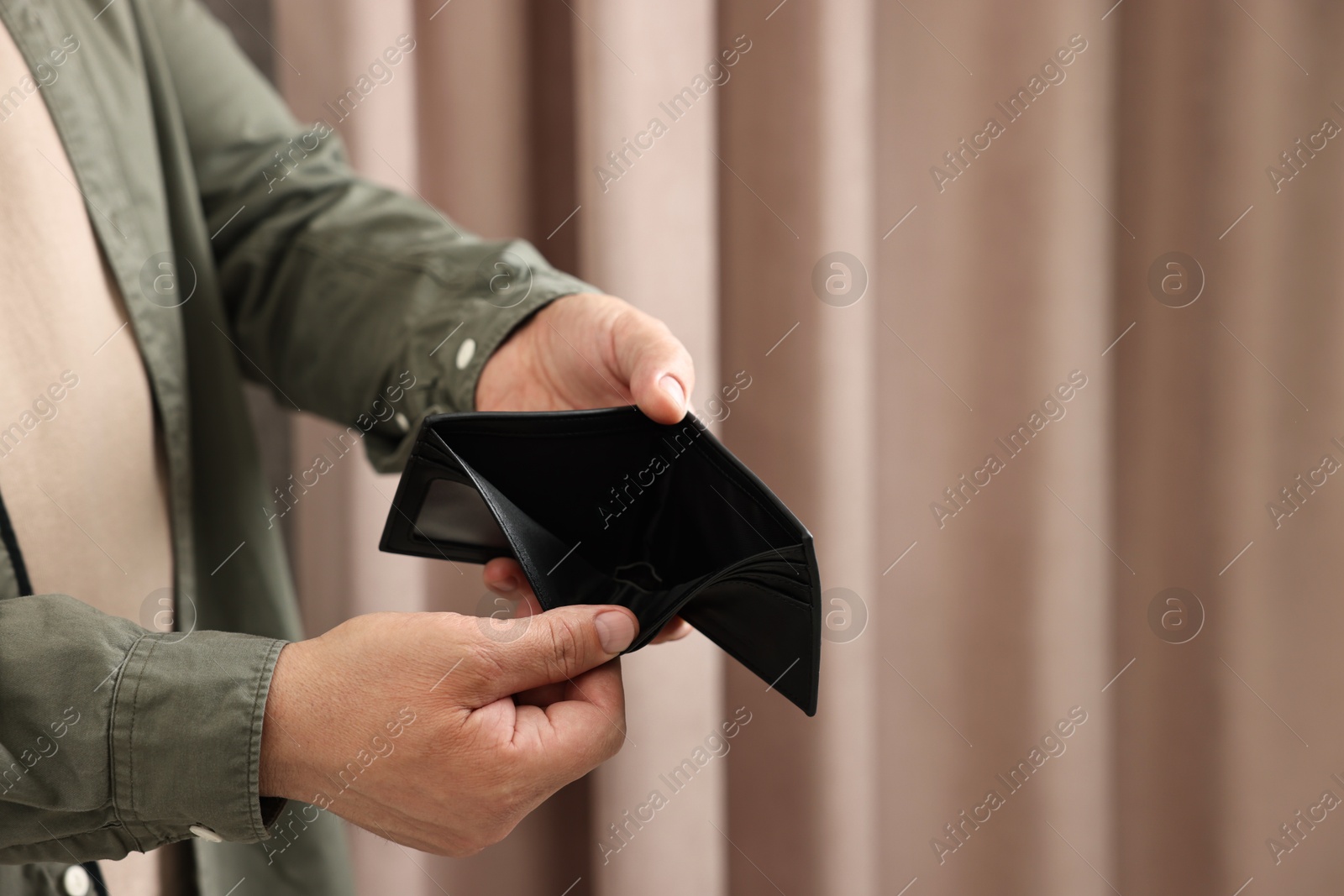 Photo of Man with empty wallet at home, closeup. Space for text