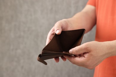 Photo of Man with empty wallet on blurred background, closeup. Space for text