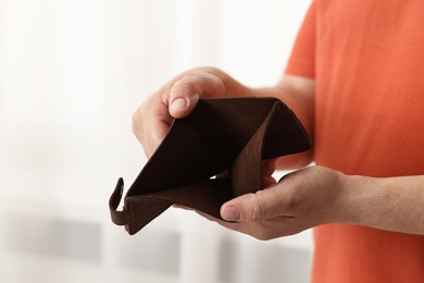 Photo of Man with empty wallet on blurred background, closeup. Space for text