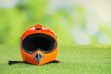 Photo of Orange motorcycle helmet with visor on green grass, space for text