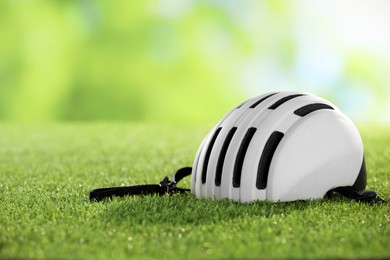 Photo of White protective helmet on green grass, space for text