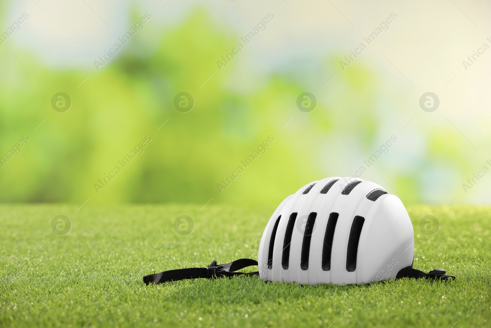 Photo of White protective helmet on green grass, space for text