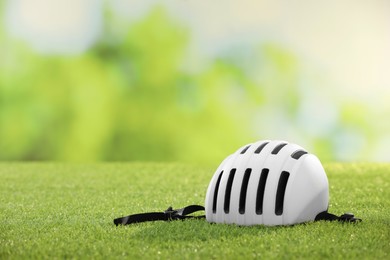 White protective helmet on green grass, space for text