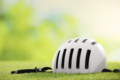 White protective helmet on green grass, space for text