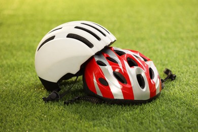 Two protective helmets on green grass. Sports equipment