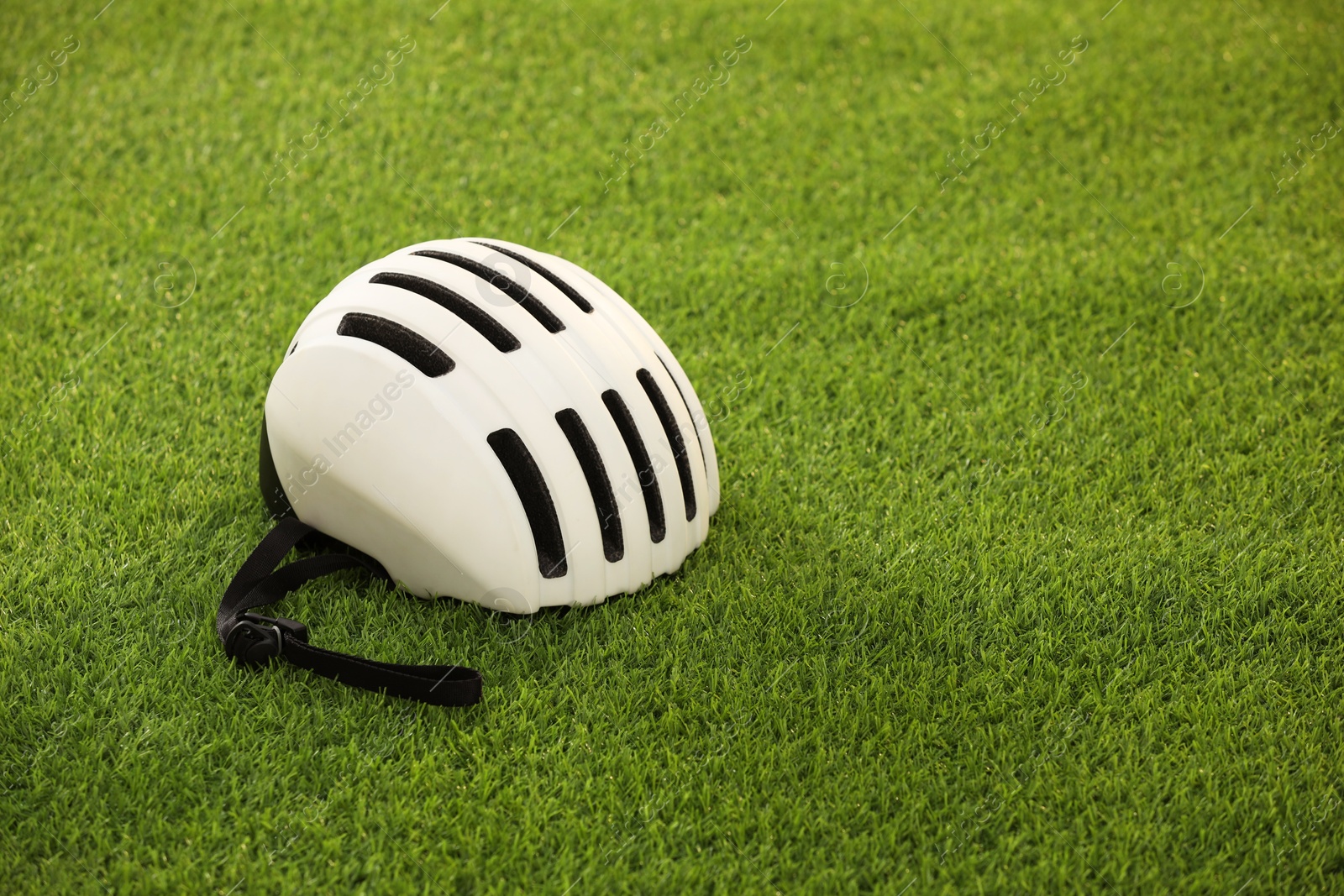 Photo of White protective helmet on green grass, space for text