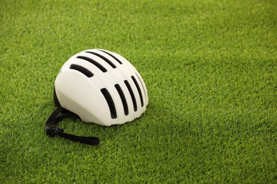 White protective helmet on green grass, space for text