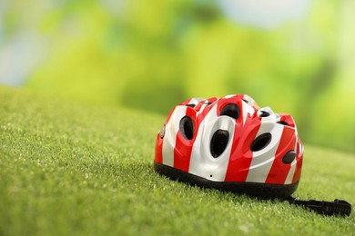 Colorful protective helmet on green grass, space for text