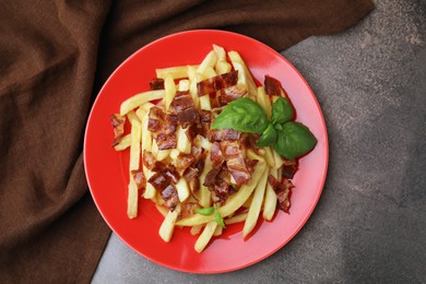 Photo of Delicious French fries with slices of bacon and basil on brown background, top view