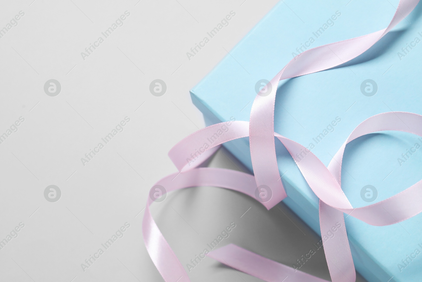 Photo of Beautiful pink ribbon and gift box on white background, above view. Space for text