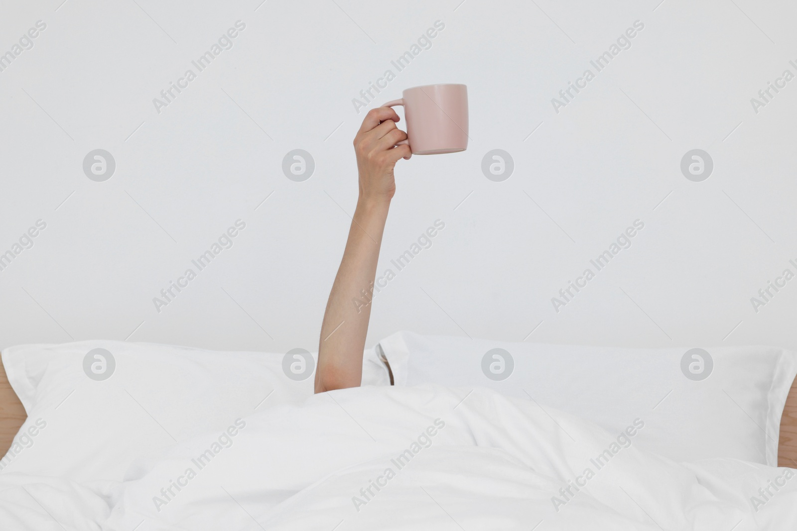 Photo of Bedtime. Woman with cup of drink in bed indoors, closeup