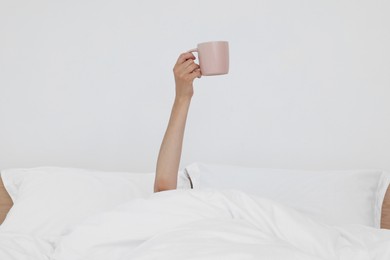 Bedtime. Woman with cup of drink in bed indoors, closeup