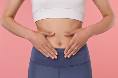 Photo of Healthy digestion. Woman touching her belly on pink background, closeup