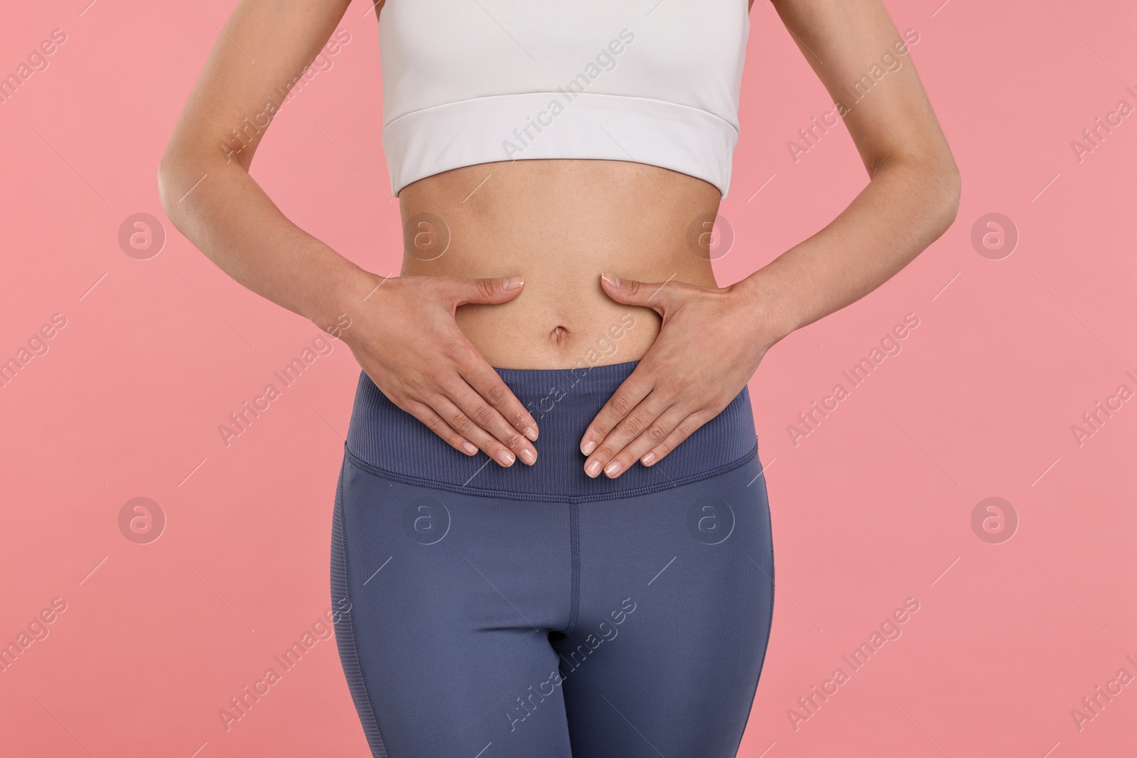 Photo of Healthy digestion. Woman touching her belly on pink background, closeup