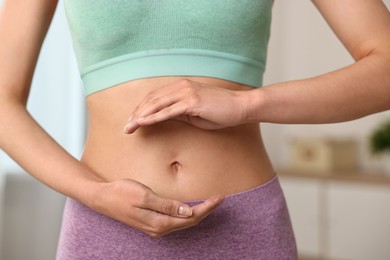 Photo of Healthy digestion. Woman holding something near her belly indoors, closeup