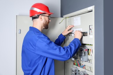 Photo of Electrician wearing uniform installing electricity meter indoors