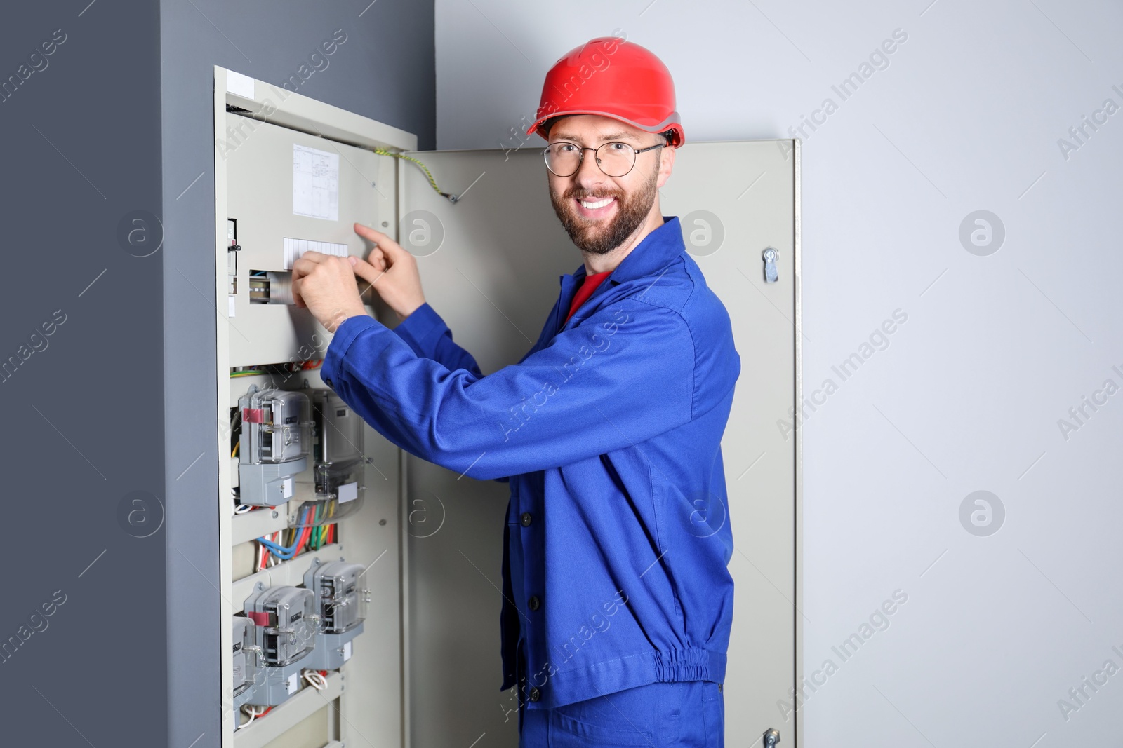 Photo of Electrician wearing uniform installing electricity meter indoors