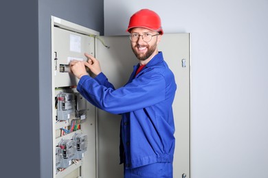 Electrician wearing uniform installing electricity meter indoors