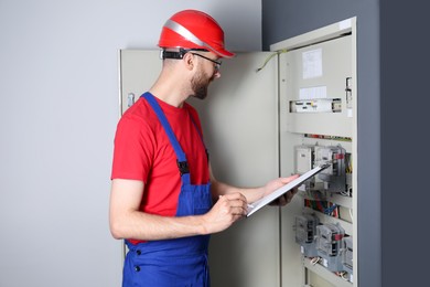 Technician worker with clipboard inspecting electricity meter