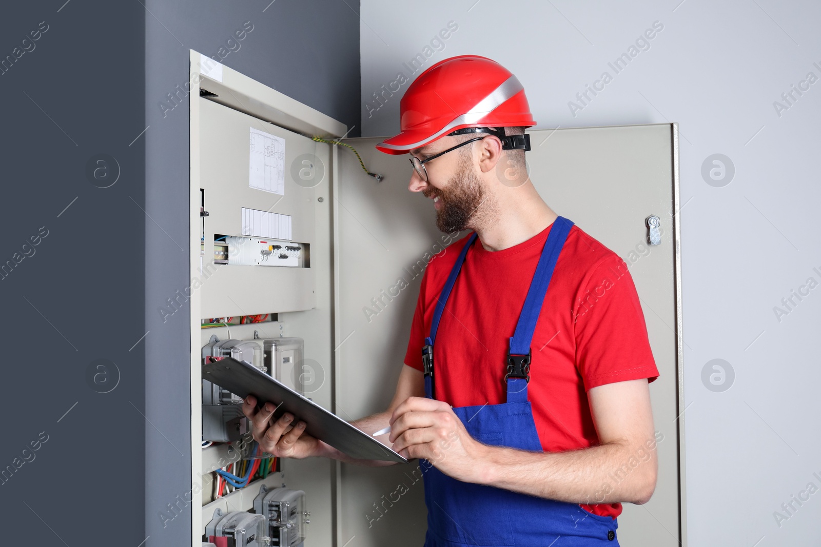 Photo of Technician worker with clipboard inspecting electricity meter