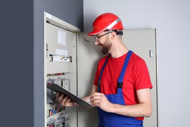 Technician worker with clipboard inspecting electricity meter