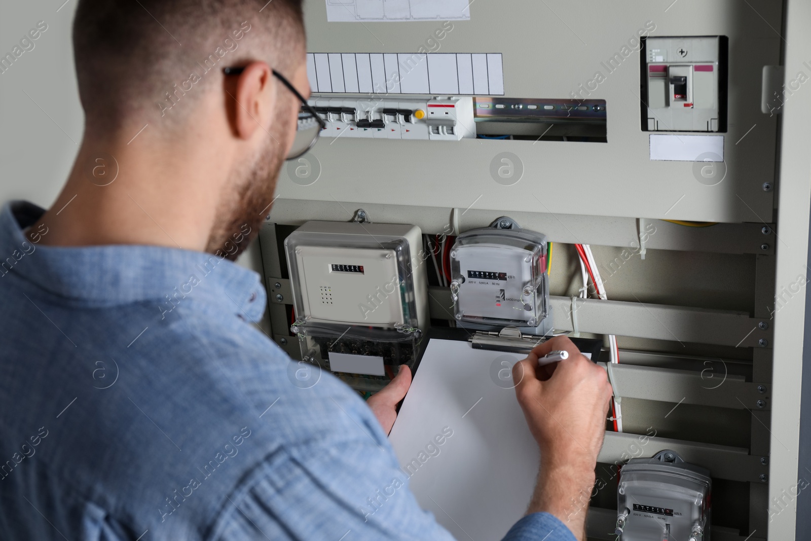 Photo of Technician worker with clipboard inspecting electricity meter, closeup