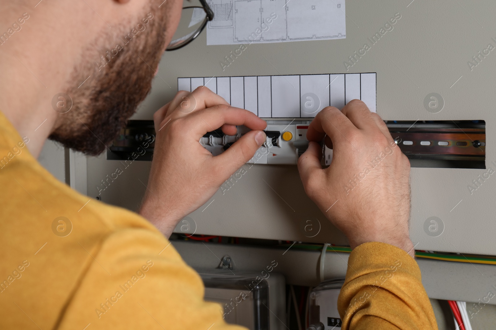 Photo of Man checking electrical fuse board indoors, closeup view