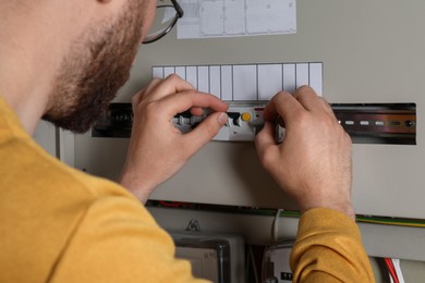 Photo of Man checking electrical fuse board indoors, closeup view